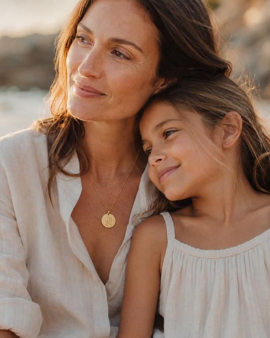 Mother and daughter in golden hour light wearing Inner Ziva Gold Heirloom Disc