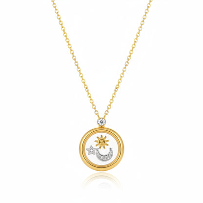 A gold-toned locket necklace with a sun, moon, and star pendant, styled on a textured cream surface next to natural stones.