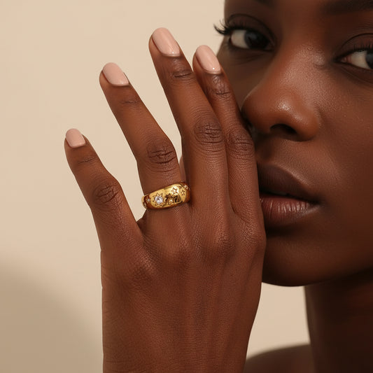 Close-up of a woman's hand wearing a gold ring with a diamond, against a neutral background.