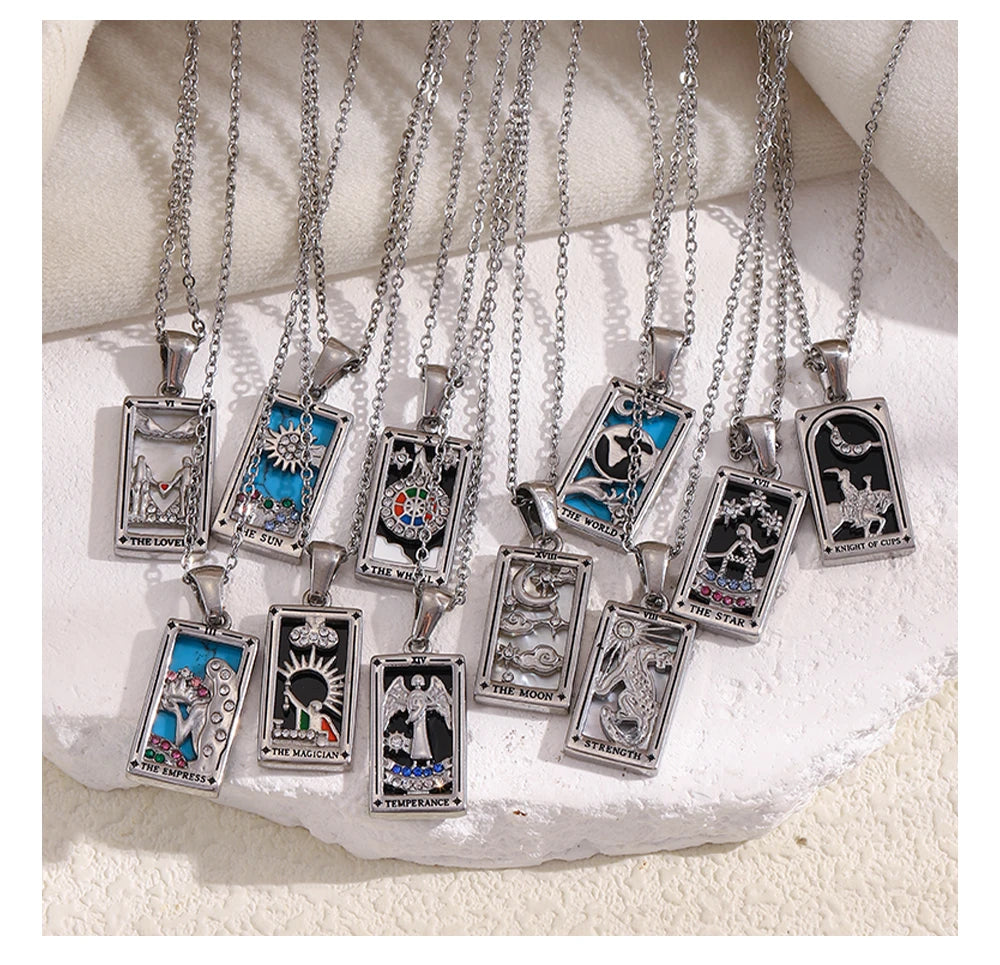 Collection of tarot card pendants on silver chains displayed on a textured white surface.