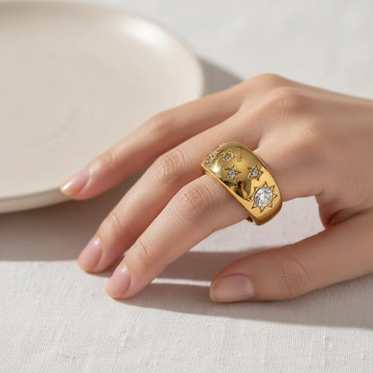 Gold ring with star designs and crystals on a white background