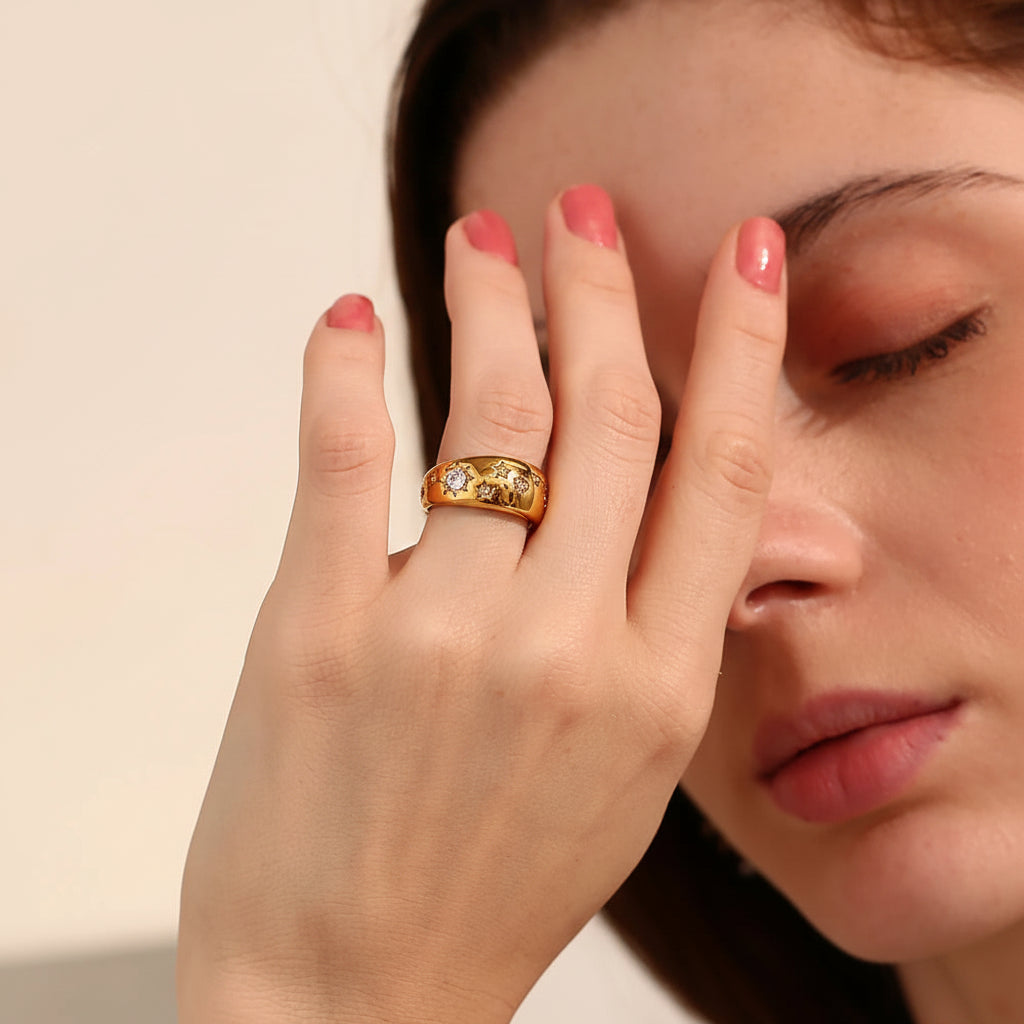 Woman wearing a gold ring with three diamonds, holding her hand to her face.