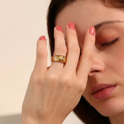 Woman wearing a gold ring with three diamonds, holding her hand to her face.