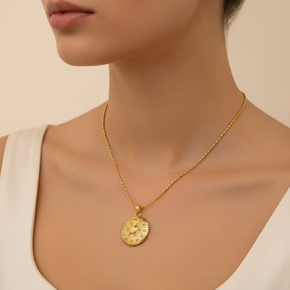 Gold necklace with a round pendant on a beige background