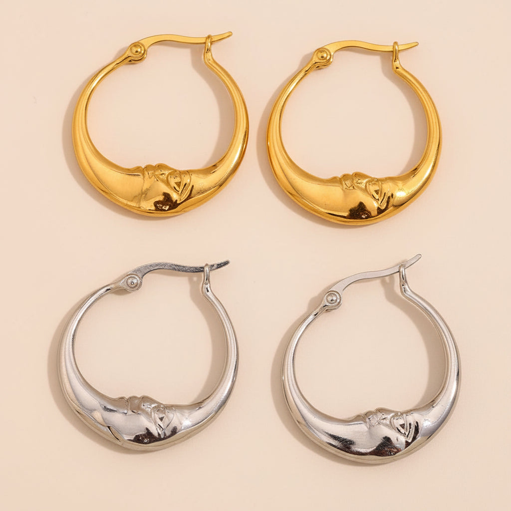 Two pairs of hoop earrings, one gold and one silver, on a beige background.