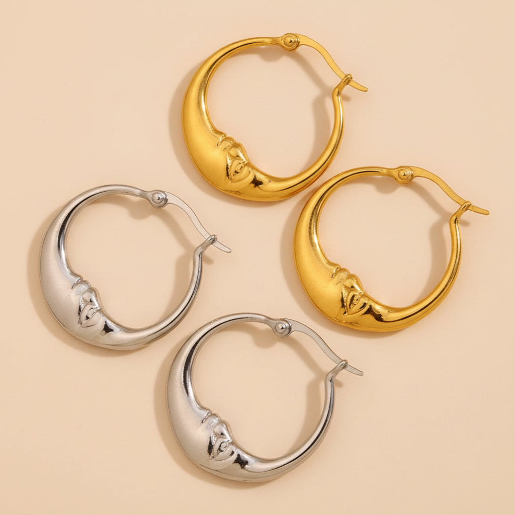 Gold and silver hoop earrings on a textured beige surface