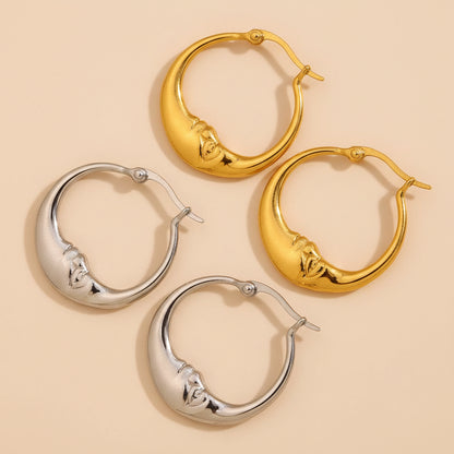 Gold and silver hoop earrings on a textured beige surface