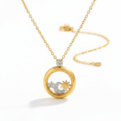 A gold locket necklace with a clear circular pendant displaying gold and silver celestial charms, resting on a white display bust.