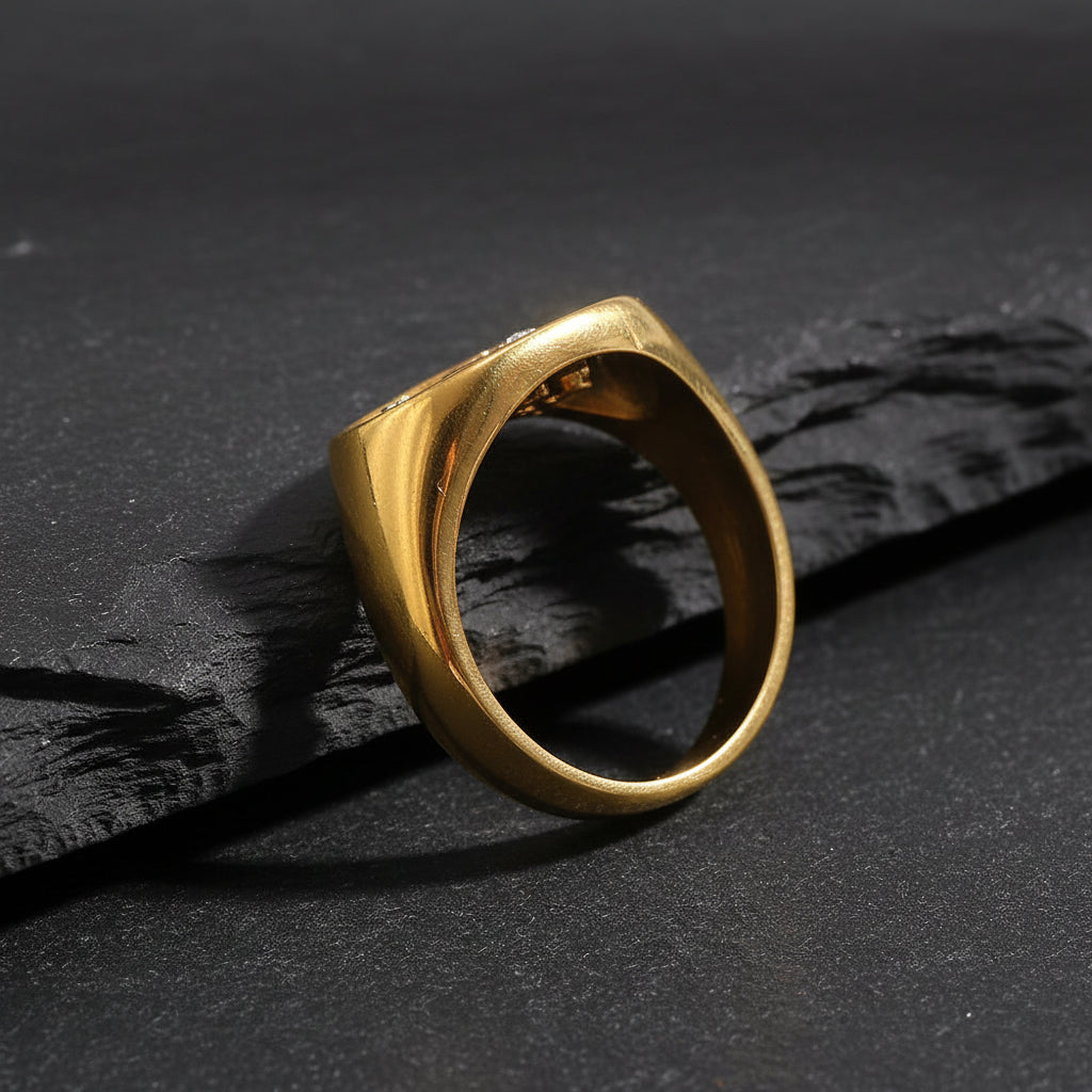 Gold ring with embedded stones on a textured white surface