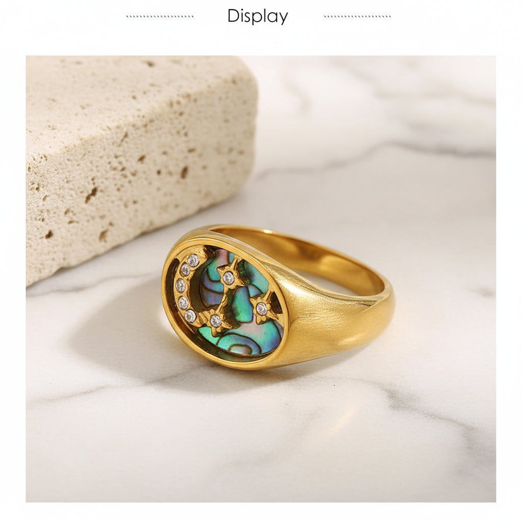 Gold ring with a central gemstone and smaller stones on a textured beige background