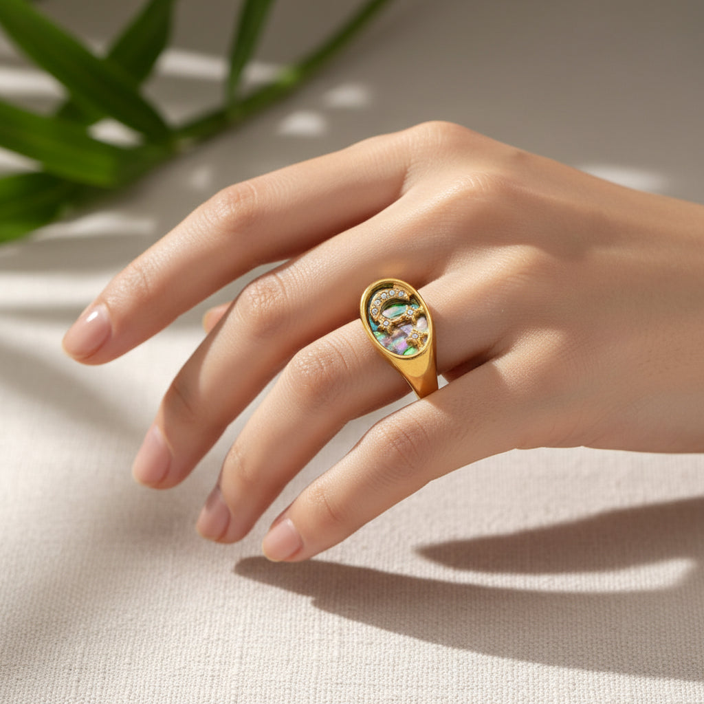 Gold ring with opal stone and star design on a white fabric background