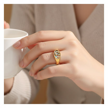 Gold ring with a central stone and star accents on a textured white background
